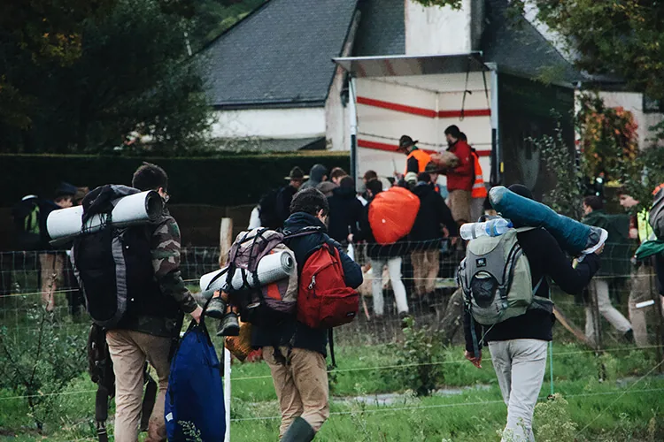 Campistas con mochila, entrando a un campamento de verano